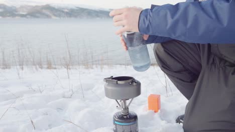 man pouring water on teapot over portable camping stove