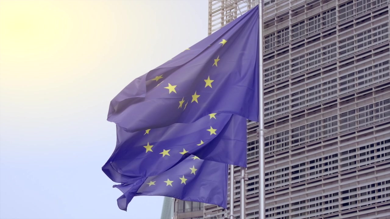 Primo piano di bandiere dell'UE che sventolano al vento vicino all'edificio della Commissione Europea a Bruxelles