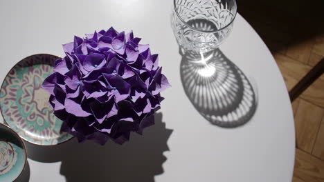 purple hydrangea arrangement with glass shadow on white table