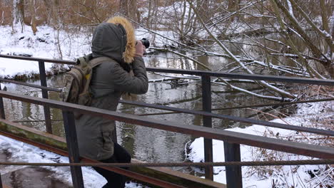 frau fotografiert beim spaziergang in der verschneiten natur.