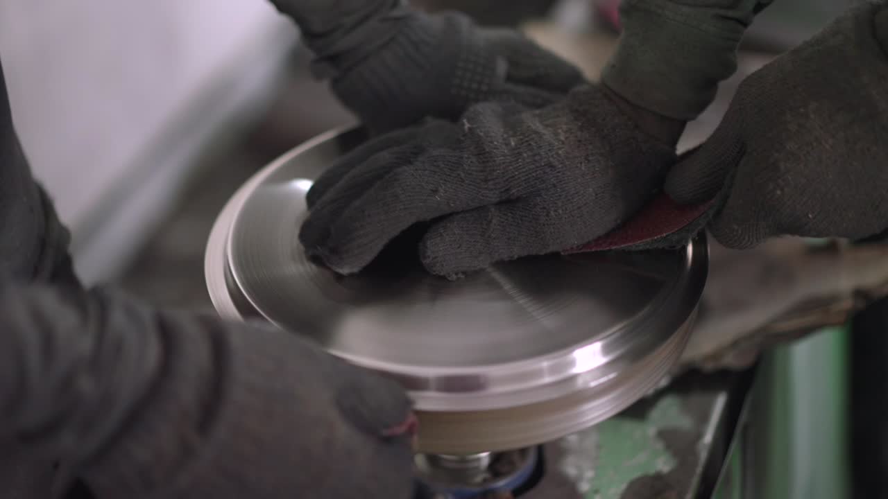 Using a belt sander to produce steel pan cookware in a factory