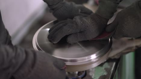 using a belt sander to produce steel pan cookware in a factory