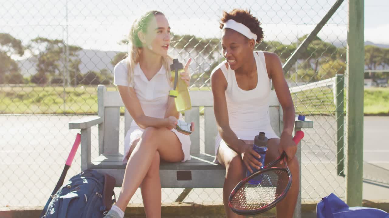 행복 한 다양한 여성 테니스 선수 들 이 경기 후 앉아서 이야기 하고 휴식을 취하는 영상