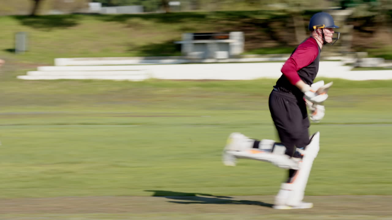 Cricket player sprinting on field wearing protective gear during match