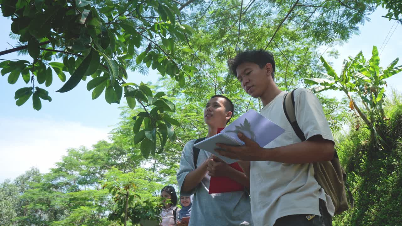 Two Asian Male Students Researching Botanical Plants In Outdoor Learning