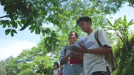 two asian male students researching botanical plants in outdoor learning