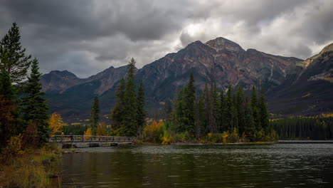 Lapso-De-Tiempo,-Isla-Piramidal-Y-Puente-Sobre-El-Lago-Piramidal,-Nubes-Oscuras-Dramáticas-Moviéndose-Sobre-Los-Picos-Del-Parque-Nacional-Jasper,-Canadá