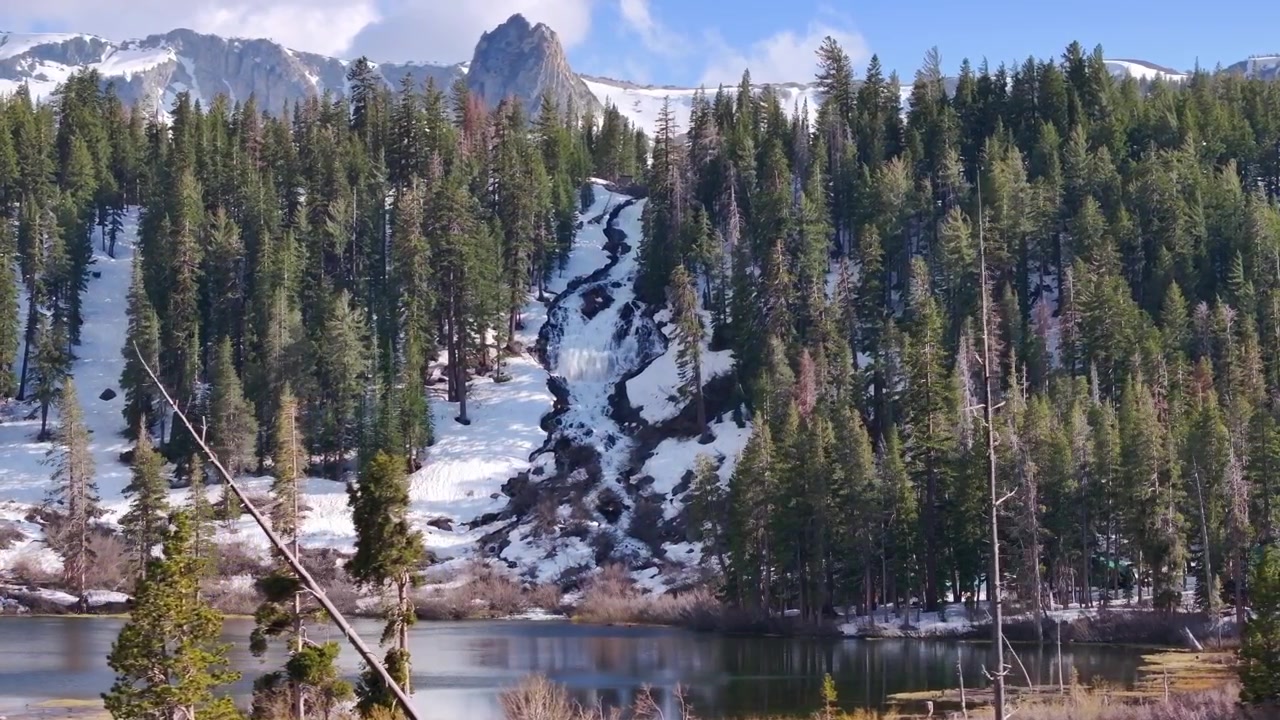 Veduta aerea cinematografica dei Twin Lakes a Mammoth Lakes, California, con foreste sempreverdi, terreno alpino aspro e cime montuose spettacolari che circondano il bacino glaciale
