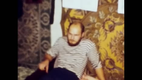 man playing guitar on bed, cultural expression in soviet era. circa ussr 1980s: a man showcasing his musical talent by playing a guitar while sitting on a bed in the context of soviet unions cultural history.