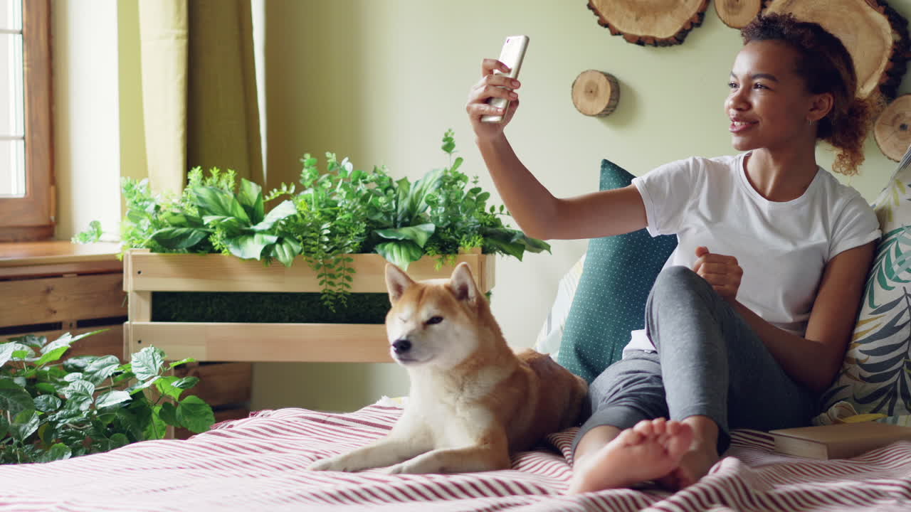 Woman taking selfie with her dog in a cozy bedroom