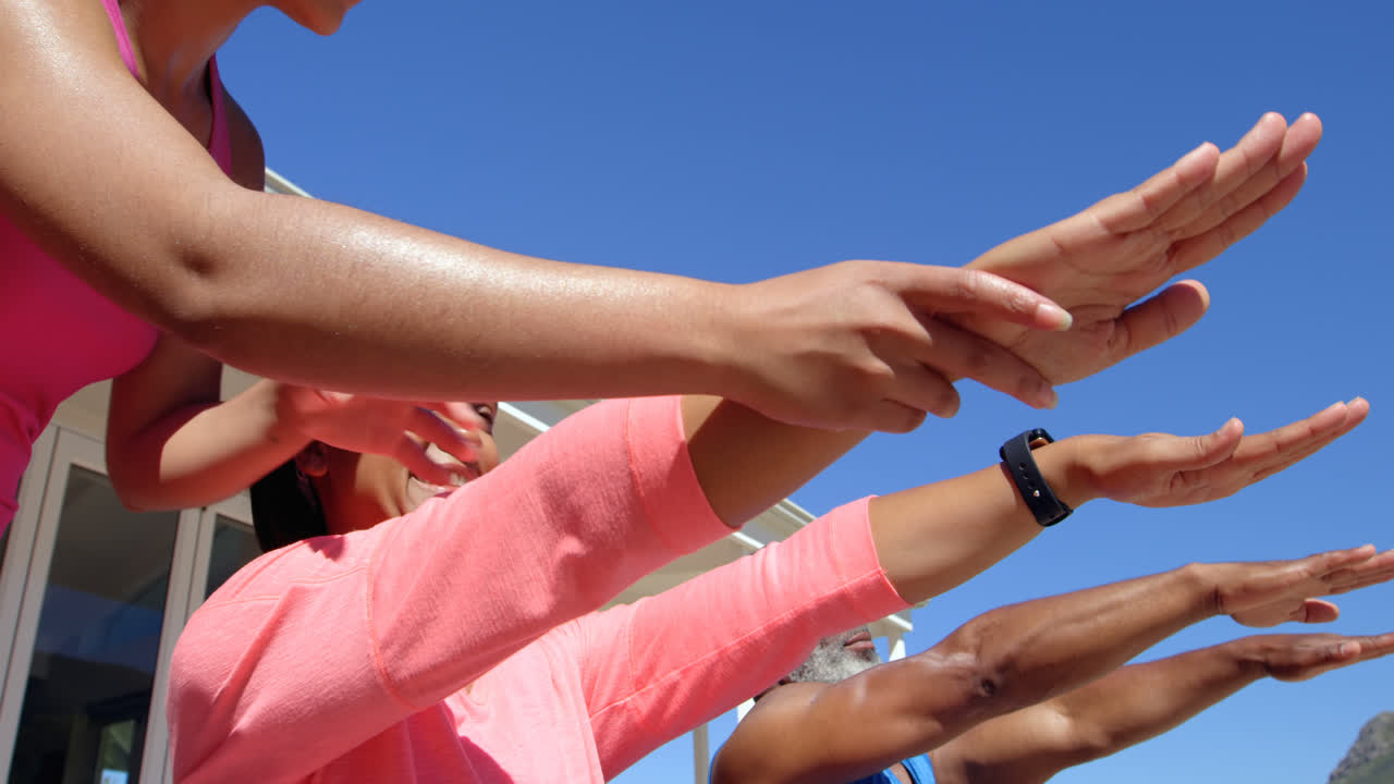 뒷마당 4k에서 성숙한 흑인 커플과 함께 운동하는 혼성 인종 여성 트레이너의 낮은 각도 뷰