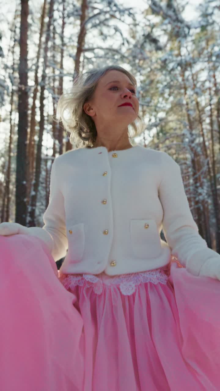Mulher elegante em saia rosa e jaqueta branca em floresta nevada