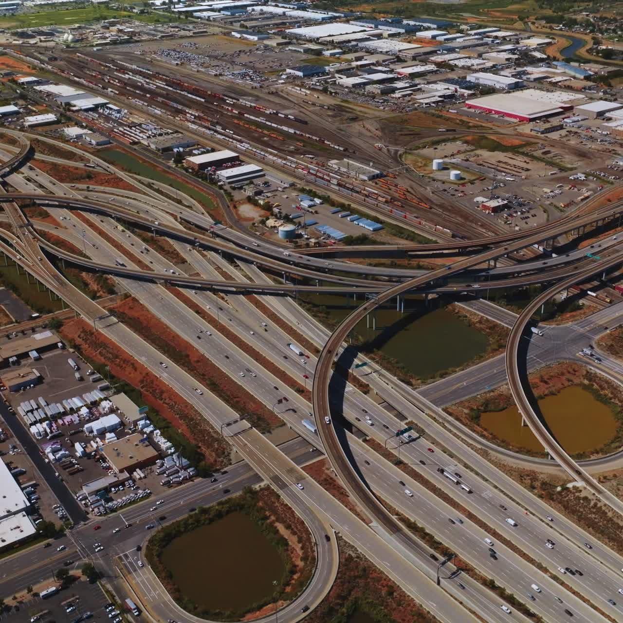 Multiple roads intertwining at the industrial area of Salt Lake City. Hundreds of cars moving by the highways of Utah. Top perspective
