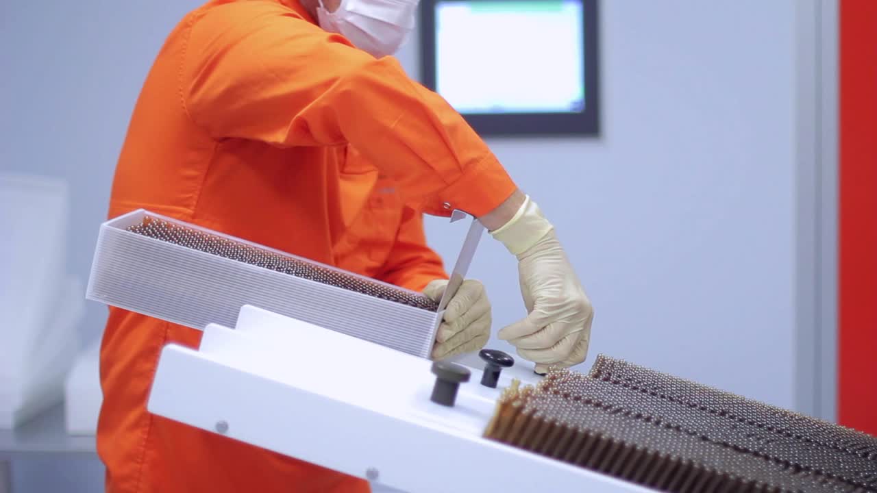 Pharmaceutical worker loading medical vials at pharmaceutical packaging machine