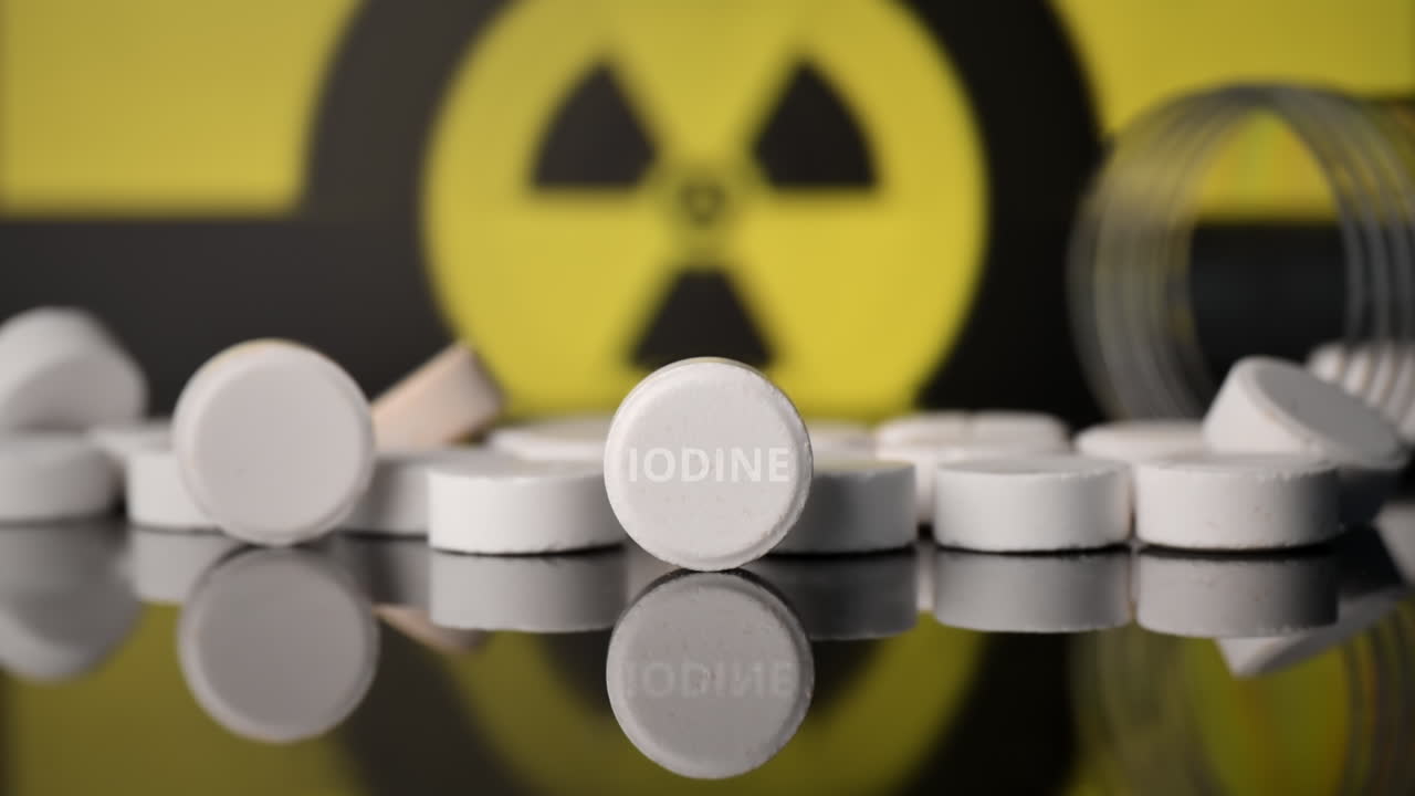 Scattered anti-radiation iodine pills, empty jar nearby, ionizing radiation sign on the background