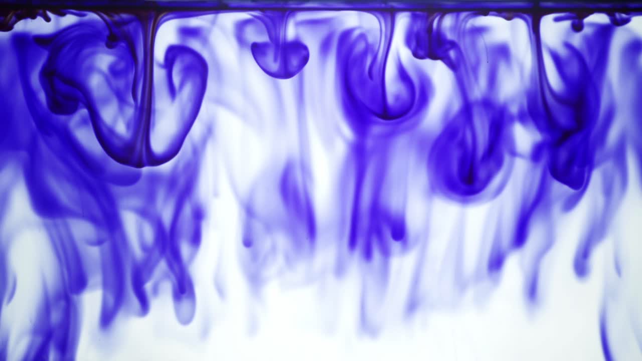 Colorful chemical liquids mix and swirl in water, forming smooth abstract patterns and organic shapes