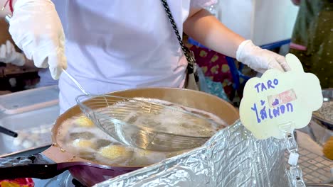 vendor frying sweet potato balls at floating market in bangkok