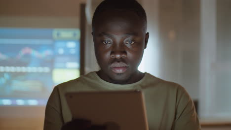 african american man working on tablet in office at night
