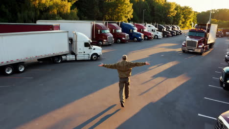 trucker running through a busy truck stop parking lot at golden hour