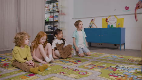 four children sitting on a carpet in a classroom at a montessori school