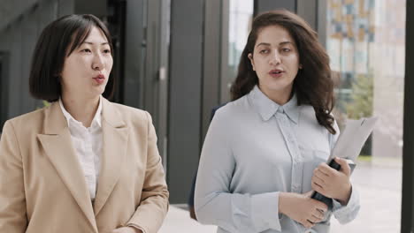 two businesswomen going along office hall and talking