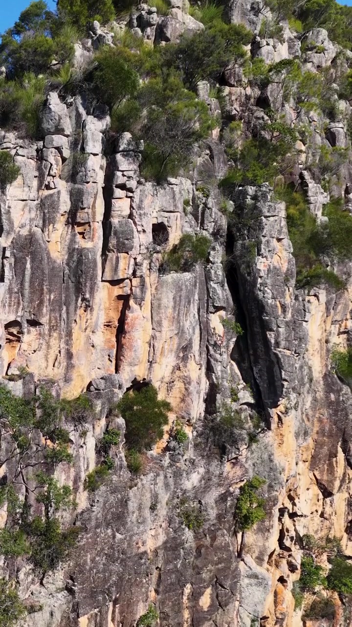 Aerial view of rugged rock formations with lush greenery under bright sunlight in Nimbin, NSW, Australia