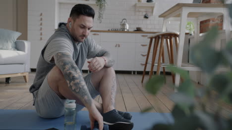 man doing home workout with dumbbells and smartphone