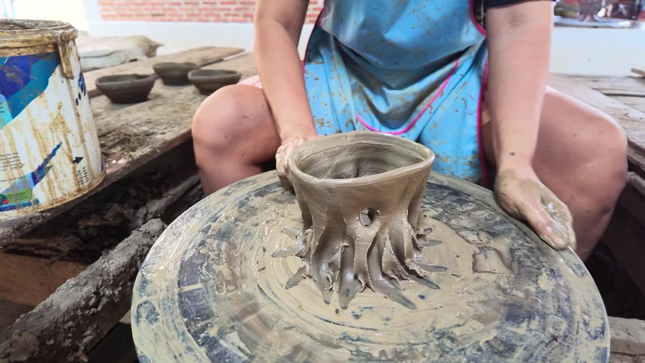 Mani artigiane modellano argilla umida su un tornio rotante in un laboratorio di Koh Kret, Thailandia.