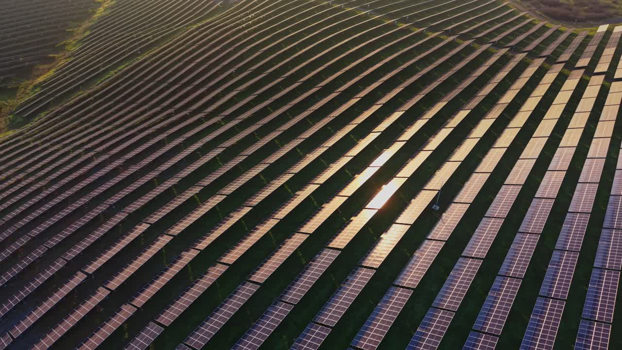 Solar panels cover fields in a renewable energy site under clear skies