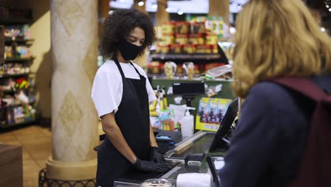 portrait of female worker at grocery store checkout with client