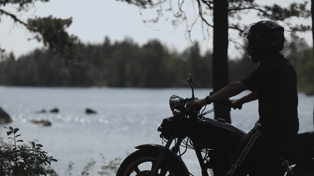 Close up of biker on motorcycle, lake in background