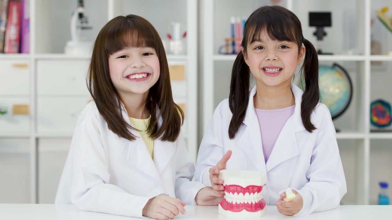 Hai học sinh nhỏ thực hành đánh răng trên mô hình răng trong bối cảnh phòng thí nghiệm khoa học lớp học sáng sủa