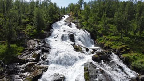 drone slowly flies up against a waterfall to reveal the river causing it