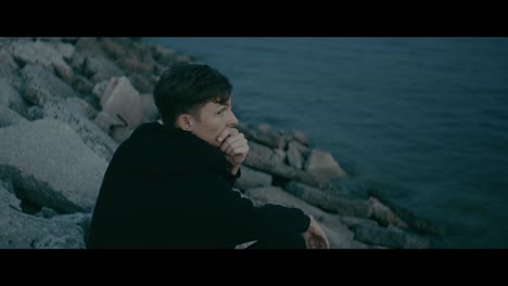man sitting on rocks by the ocean