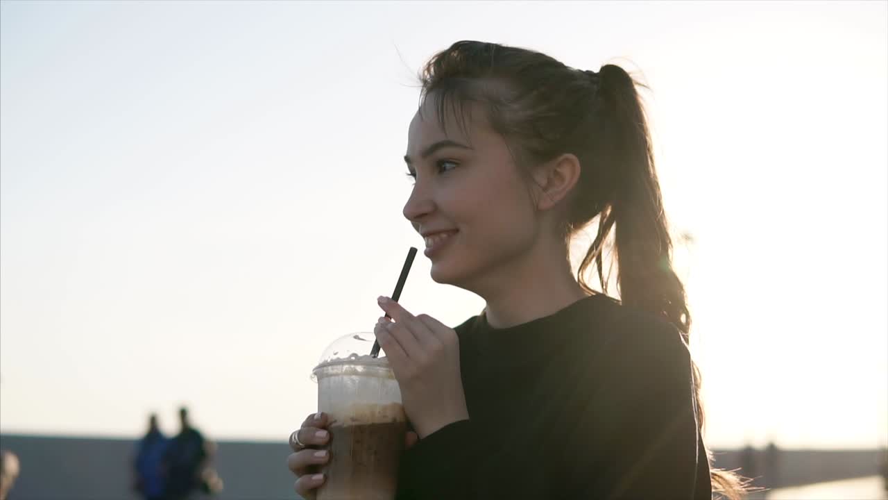 젊은 여성이 야외에서 얼음 커피를 즐기고 있습니다.