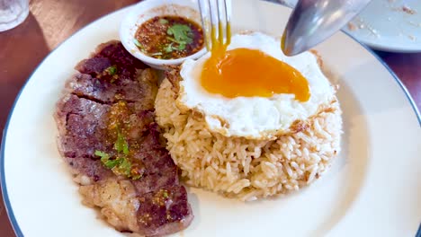 yema de huevo cortada en rodajas sobre bistec y arroz