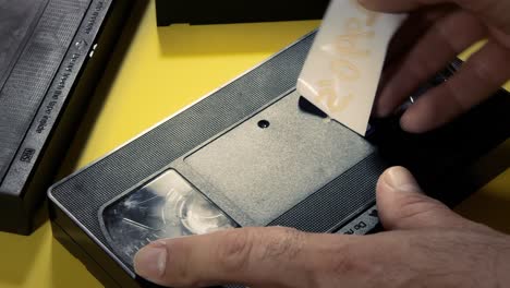 applying a white label on a vhs tape, with the handwritten text 1990s