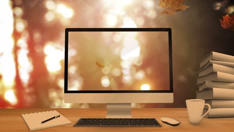 desktop computer and office equipment on a table against autumn maple leaves falling in background