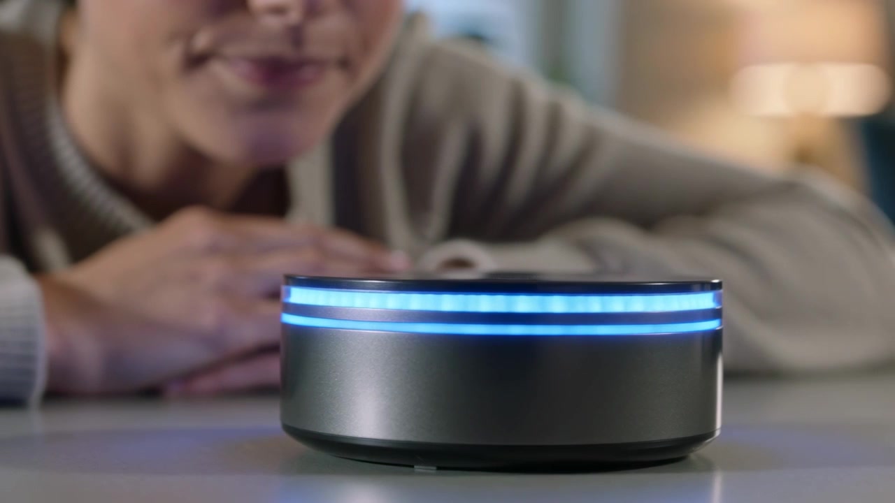 Donna che parla, richiedendo una risposta, mentre si appoggia a un tavolo in soggiorno, con un anello LED blu in scansione.