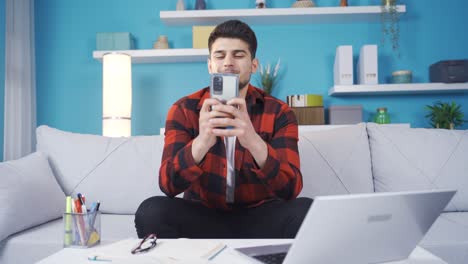 Fröhlicher-Und-Fröhlicher-Junger-Mann,-Der-Konzentriert-Auf-Das-Telefon-Schaut.