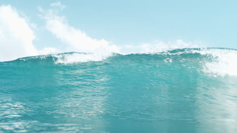 Crashing bright turquoise wave curling in super slow motion against sky