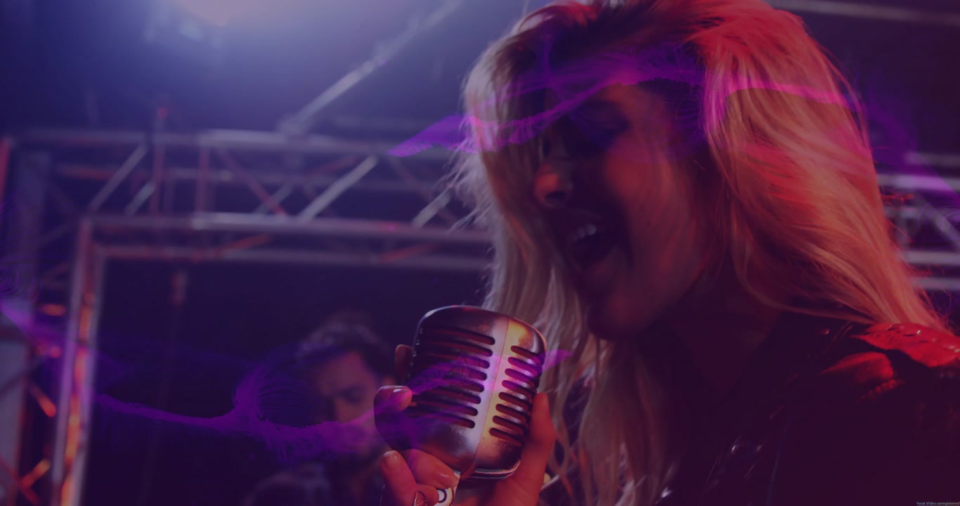 Lead singer starting song on music stage, leaning into mic while purple streaks revealing guitarist