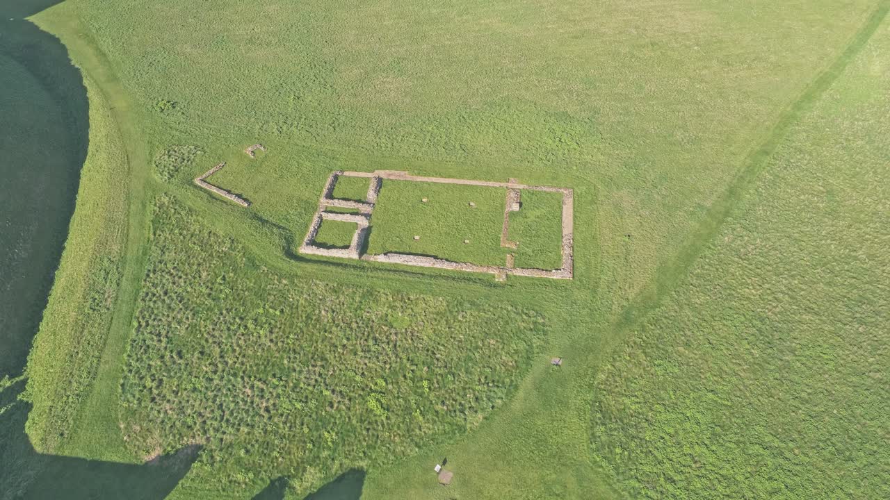 Scarborough Castle North Yorkshire UK archaeological remains, stone foundations and earthworks within grassy enclosure on elevated headland above North Sea coastline, smooth drone descent shot