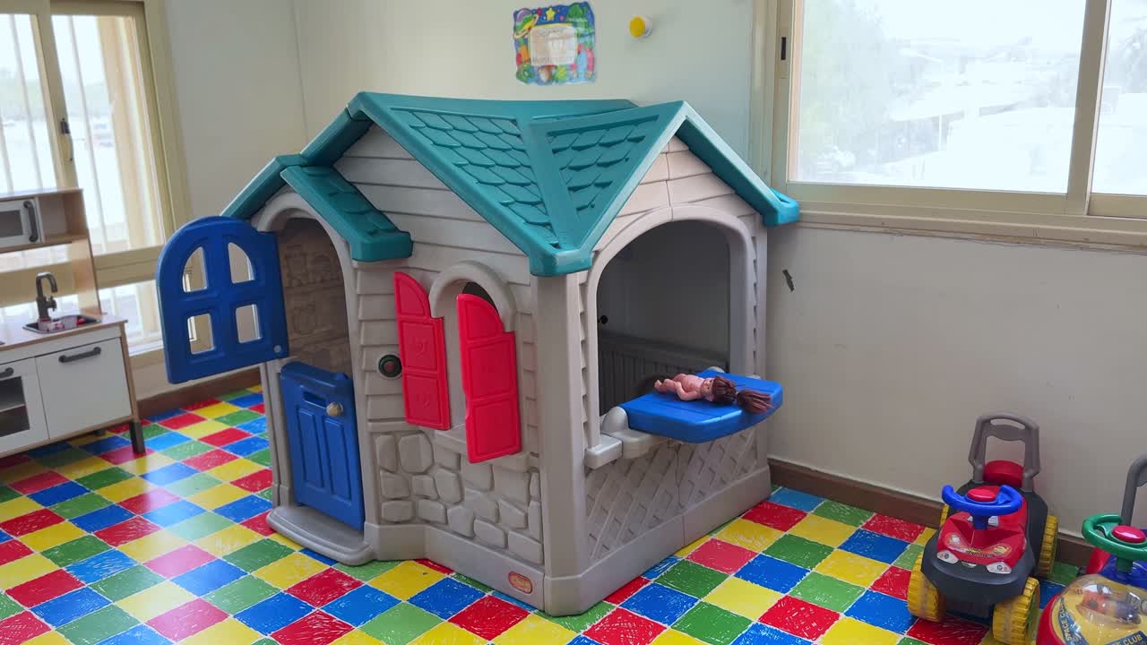 Static 4K shot of a vibrant playhouse in a daycare setting, featuring toys, colorful flooring, and natural light. Ideal for education, childhood, or preschool themes.