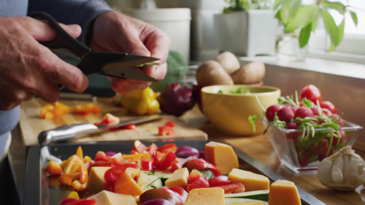 sección media de un hombre caucásico de pie en la cocina, cocinando la cena y cortando verduras