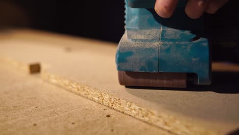 using a handheld sander on particle board