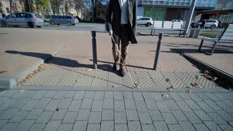 lone blind man detecting tactile tiles, walking to pedestrian crossing safe road