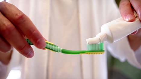 midsection of biracial man putting toothpaste on toothbrush, slow motion