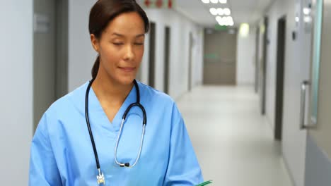 smiling doctor with medical report standing in corridor