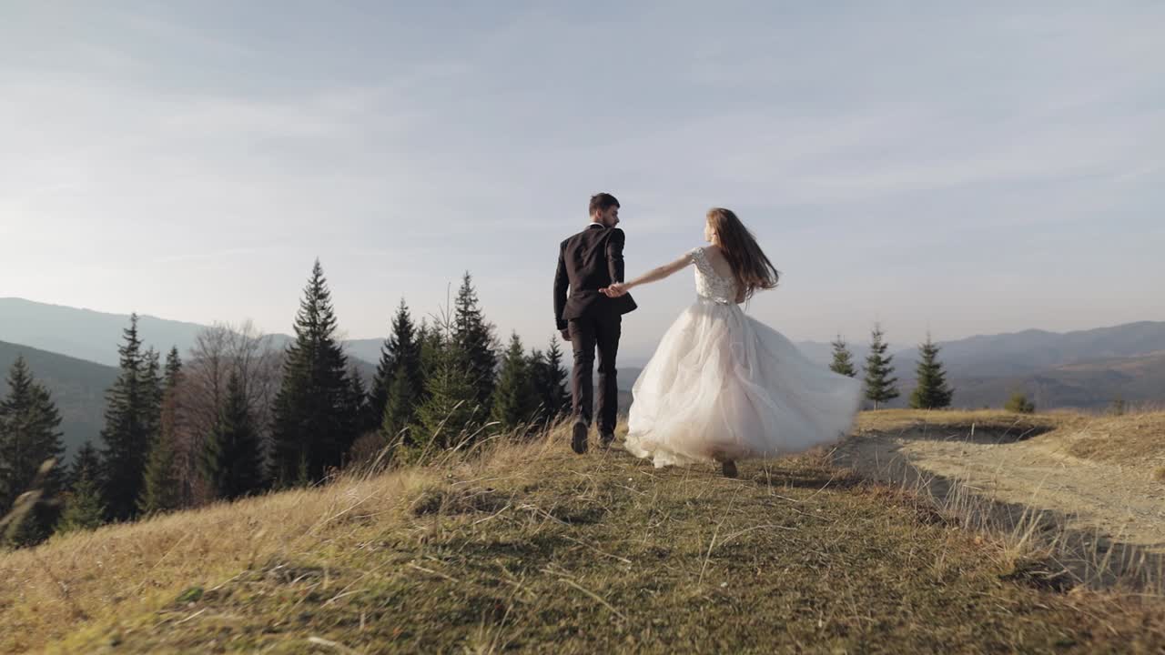 Nybrudepar. Kaukasisk gom med brud løber på en bjergskråning. Bryllupspar.